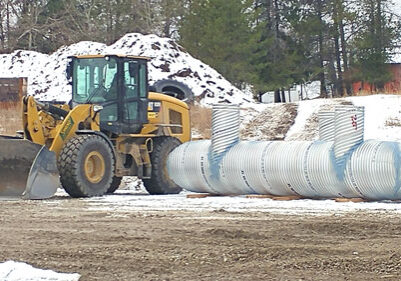 A bulldozer is parked next to a large tank.