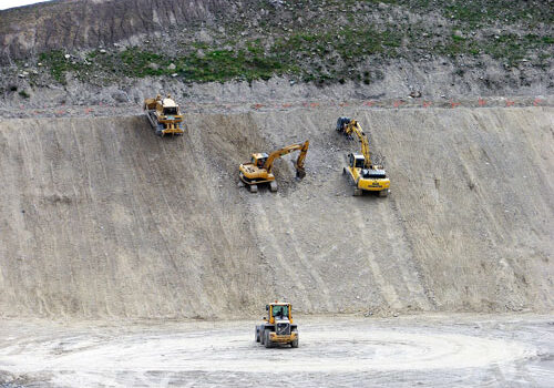 A group of excavators working on a hillside.